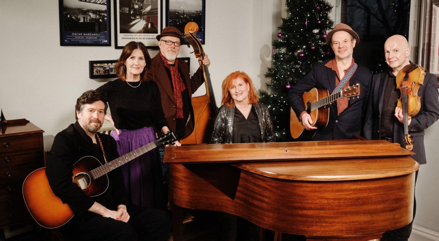Musicians Eddi Reader, Karen Matheson, John McCusker, Kris Drever, Ian Carr and Kevin McGuire gathered around a piano