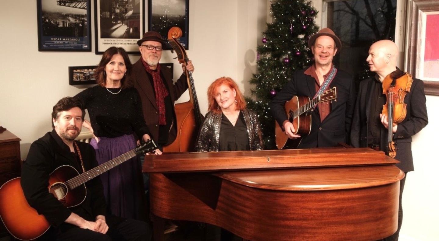 Musicians Eddi Reader, Karen Matheson, John McCusker, Kris Drever, Ian Carr and Kevin McGuire gathered around a piano
