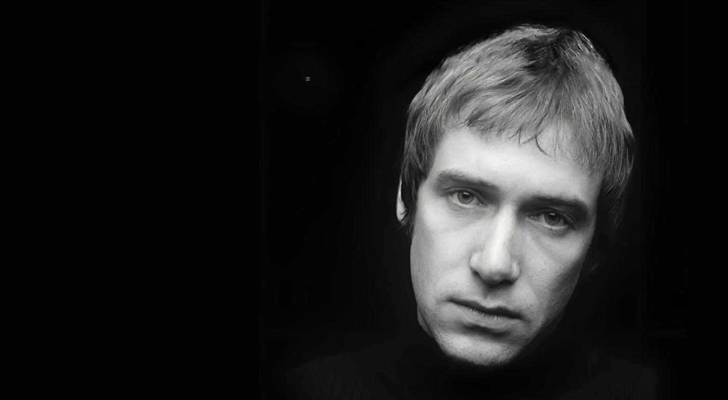 A head shot of Simon Fowler in black and white against a black background