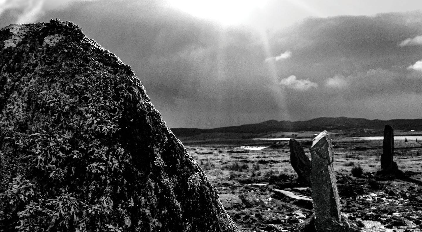 A black and white landscape with standing stones