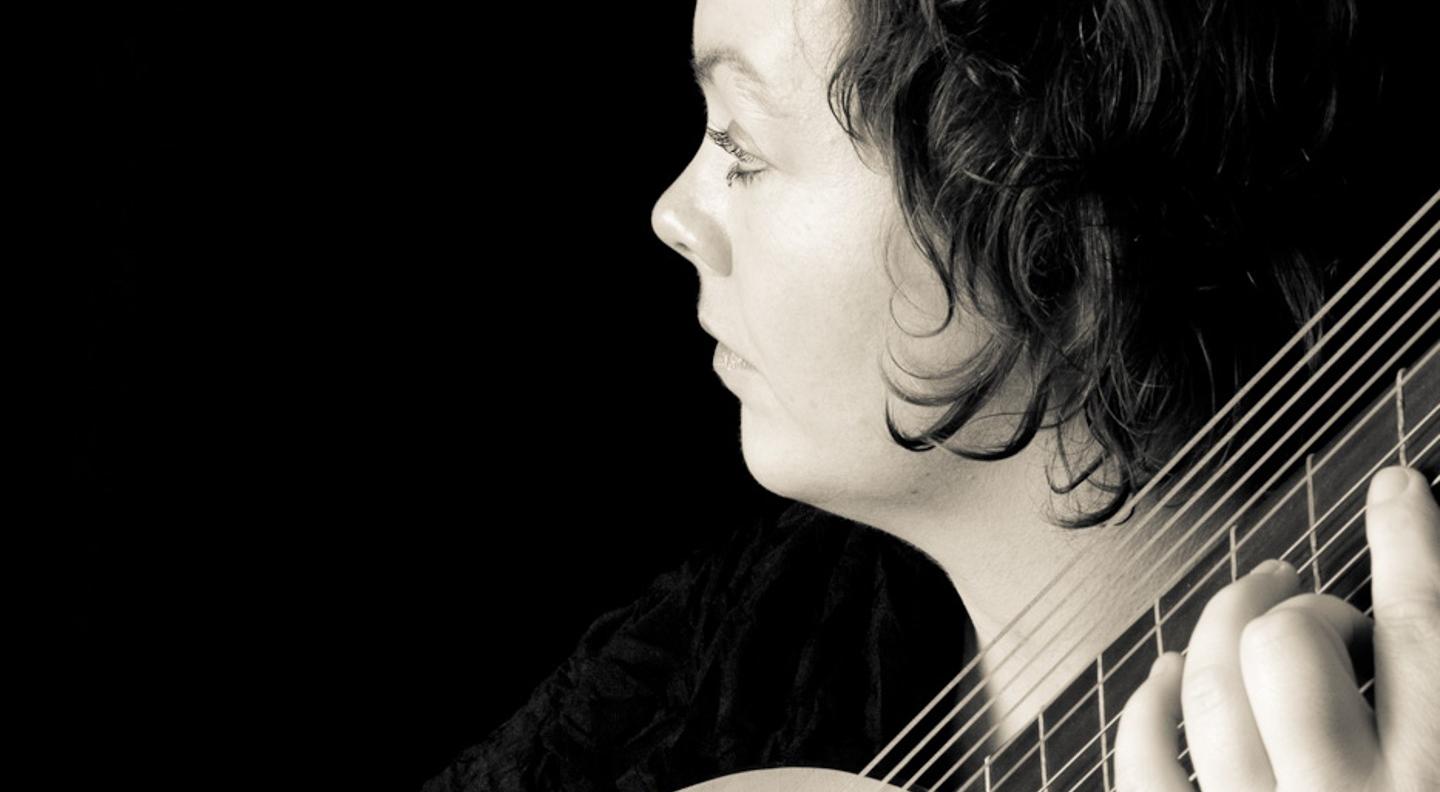 A black and white side-on close-up of Sophie Vanden Eynde playing theorbo