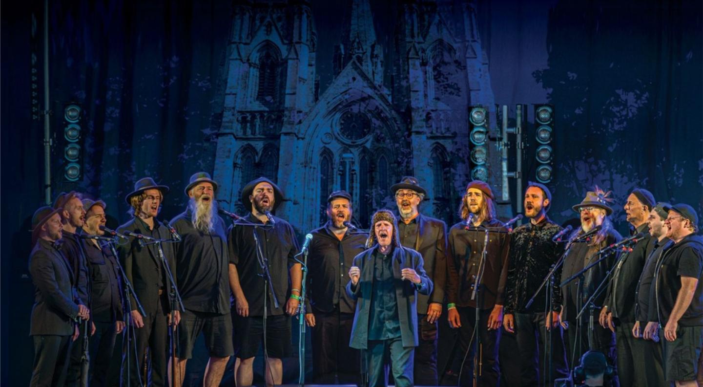 The Spooky Men's Chorale singing in front of a backdrop image of St Mary's Cathedral