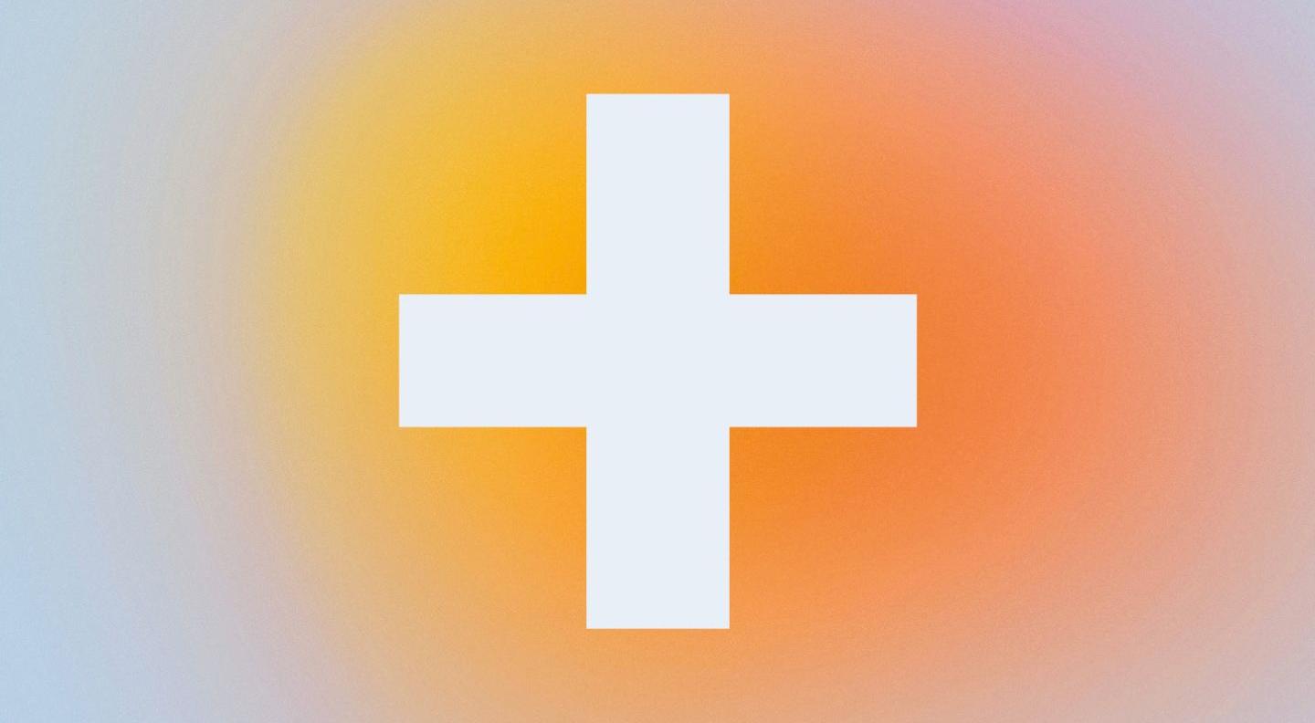 A white plus against a background of an orange, yellow and white blur