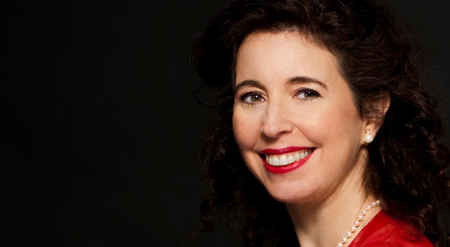  Angela Hewitt  smiling at the camera stood against a  dark background 