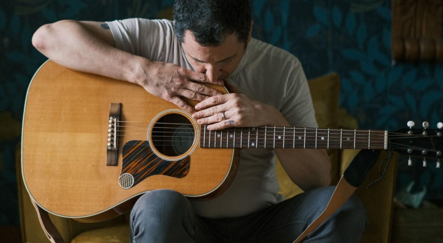 Dan Willson (Withered Hand) sitting with his guitar on his knee