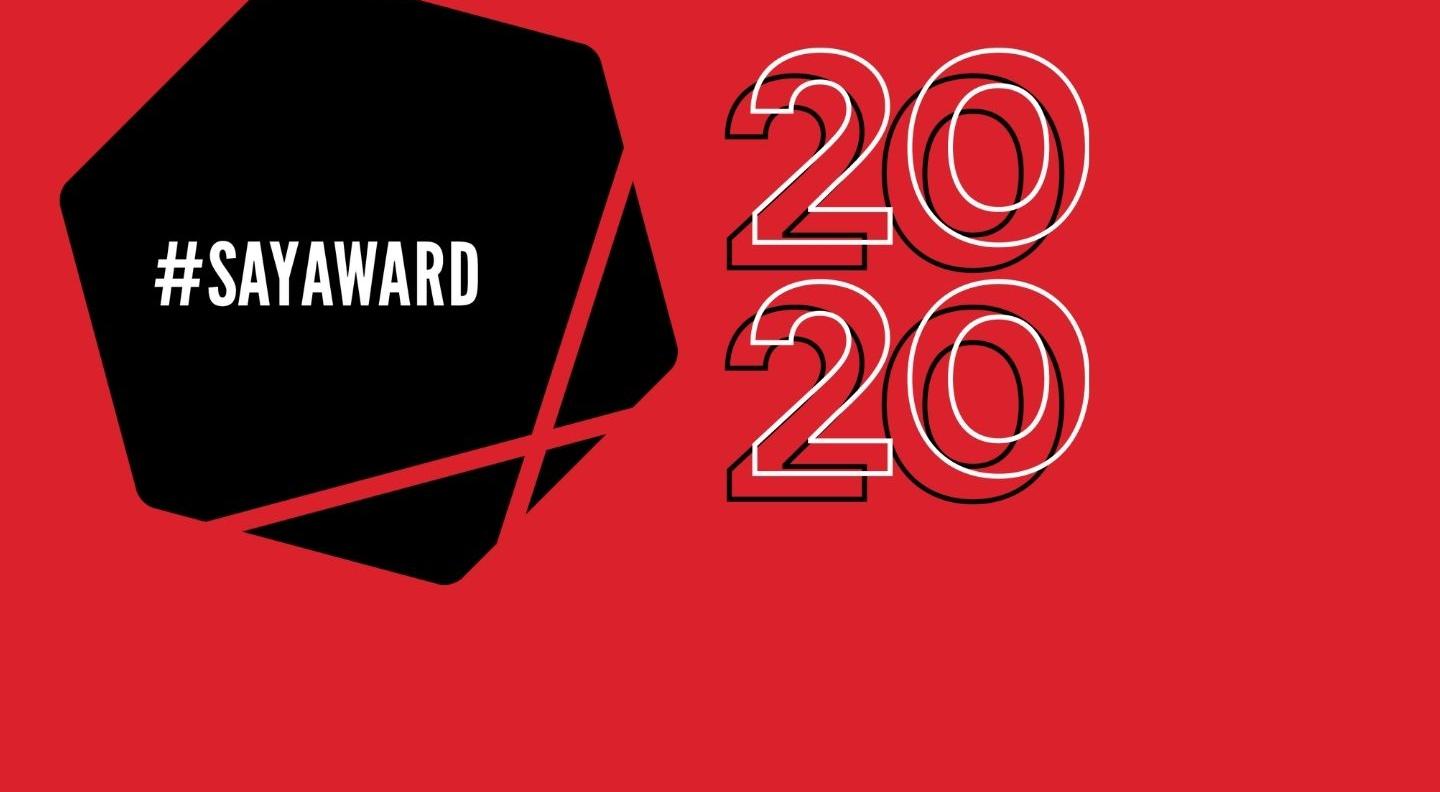 The Scottish Album of the Year Award logo is a black hexagon with two dissecting lines across the bottom half and hashtag SAY Award in white writing. 2020 is outlined in white to the right of the logo and both sit on a red background