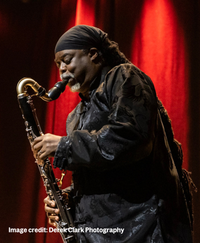 Courtney Pine - a black man with long dreads - wears dark clothes and plays the saxophone with his eyes closed