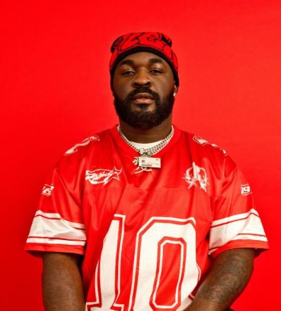 Pillz the Energiser wearing a red American Football top, sitting in front of a red background