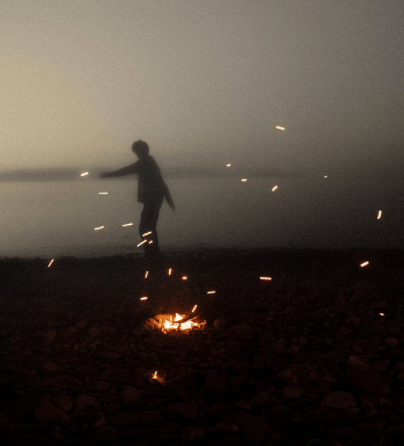 a smoky scene with a silhouette dancing on the embers of a fire